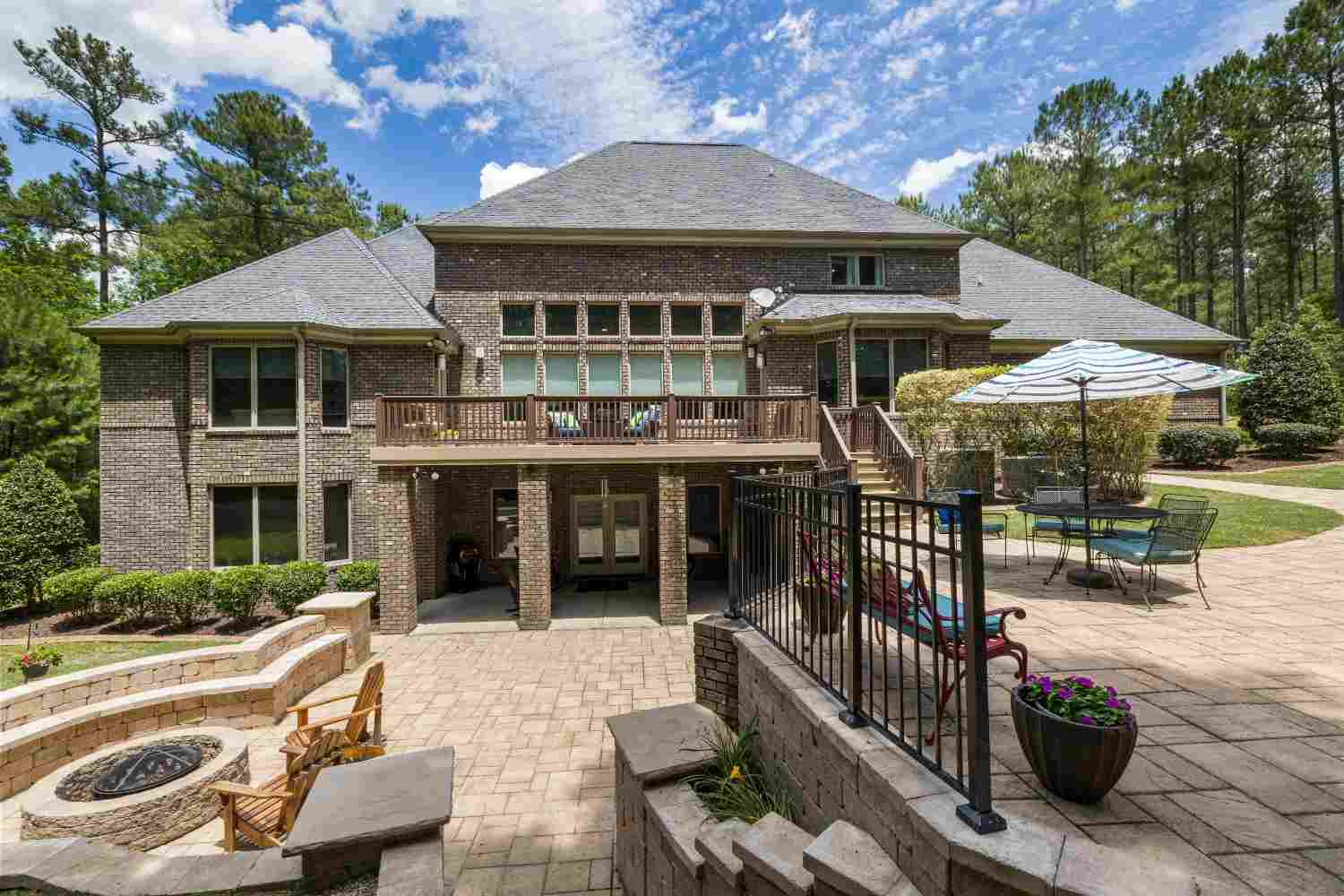 Brick residence with a deck and paver patio around a fire pit