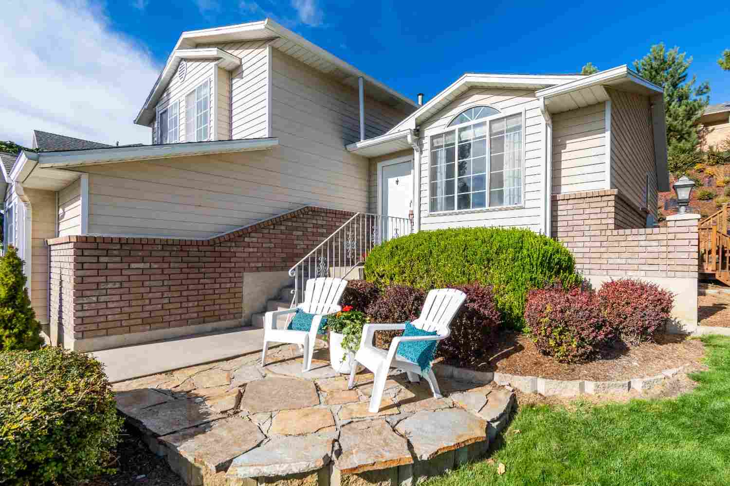 Split-level residence with brick base and a flagstone patio