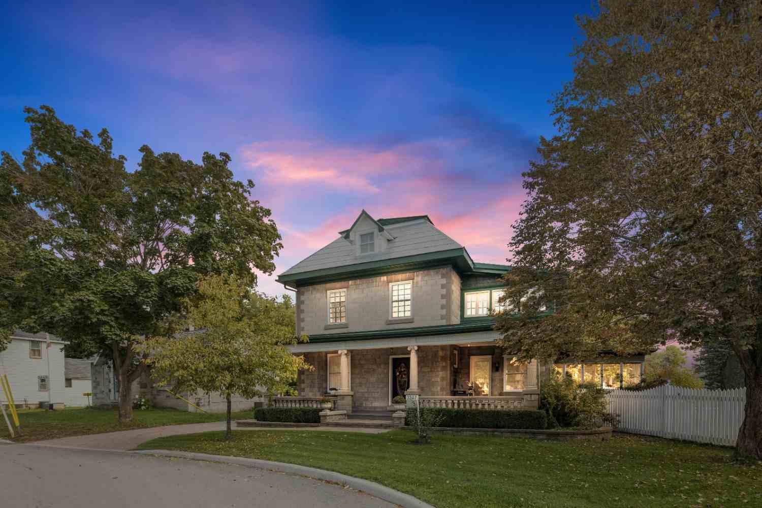 Stone-fronted historic house with a columned porch and clipped hedges